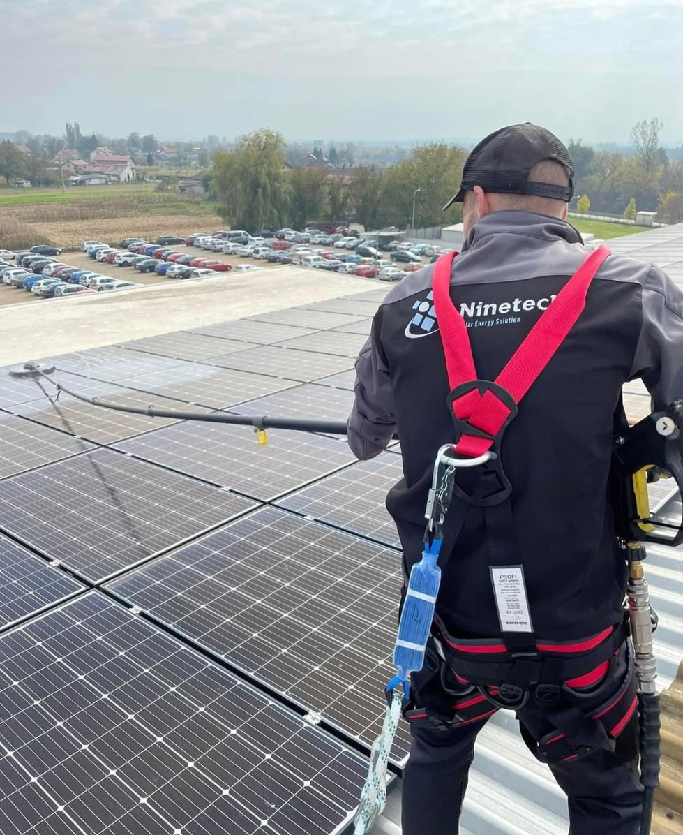 Ninetech djelatnik u sigurnosnom pojasu pere solarne panele na krovu elektrane u Karlovcu